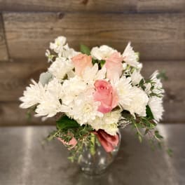 Pink roses and white daisies arranged in a clear glass vase