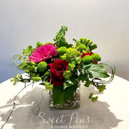 Mixed floral arrangement with red roses and a pink gerbera daisy in a glass vase