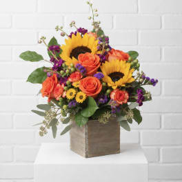 Sunflower and orange rose arrangement in a wooden cube vase