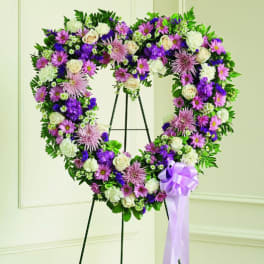 Heart-shaped floral wreath on a stand with a lavender ribbon