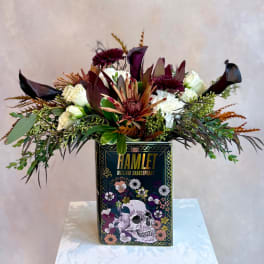Floral arrangement in a Hamlet book-shaped container with dark blooms and white roses