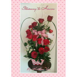 Tall arrangement of red roses in a chevron-patterned container with a heart accent