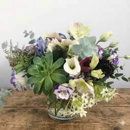 Mixed bouquet with succulents, calla lilies, and purple flowers in a glass vase