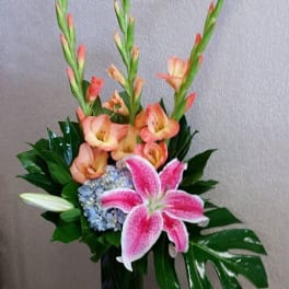 Pink lily and peach gladiolus arrangement in a blue vase
