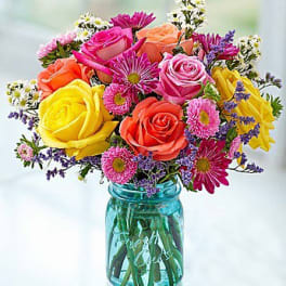 Colorful bouquet of roses and daisies in a blue glass jar