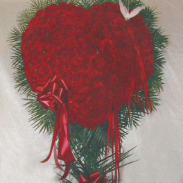 Heart-shaped red floral wreath with ribbon accents
