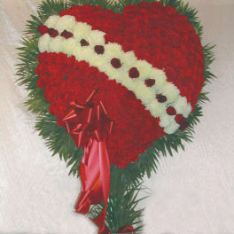 Heart-shaped red and white floral arrangement with a red ribbon