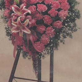 Pink carnation standing spray with lilies on a black easel