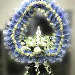 Blue and white floral funeral wreath with a small statue in the center