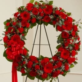 Red floral wreath on a black easel with a red ribbon