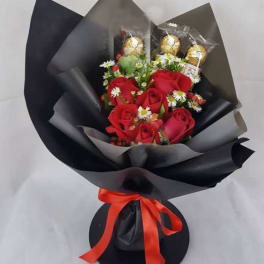 Bouquet of red roses with small white daisies and gold-wrapped chocolates