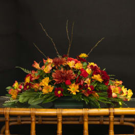 Low floral arrangement with red, yellow, and orange blooms
