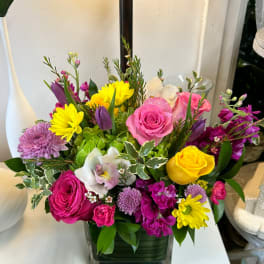 Mixed bouquet of roses, orchids, and daisies in a glass vase