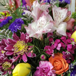 Colorful mixed bouquet with pink alstroemeria, orange rose, yellow tulip, and purple mums.