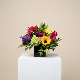 Colorful mixed flower arrangement in a black square vase