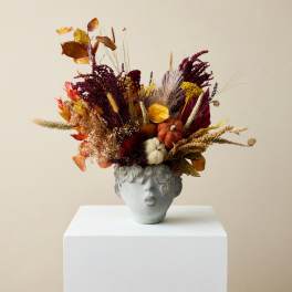 Autumn floral arrangement in a gray sculpted face vase