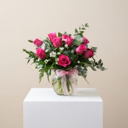 Pink roses in a clear glass vase with a pink ribbon