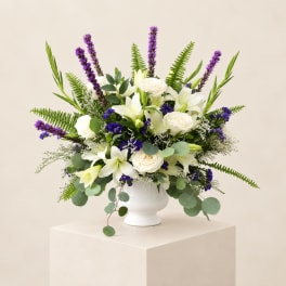 White lilies and roses in a white vase with purple accents