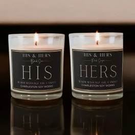 Two lit glass candles labeled HIS and HERS on a dark surface