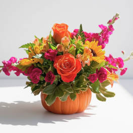 Orange and pink flower arrangement in a pumpkin-shaped container