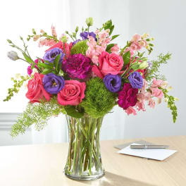 Mixed bouquet of pink and purple flowers in a clear glass vase