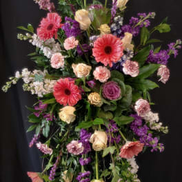 Tall floral spray with pink gerberas, cream roses, and purple blooms