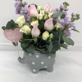 Pink and white roses in a gray polka-dot elephant planter with a baby sign