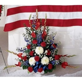 Red, white, and blue floral spray in front of a draped flag