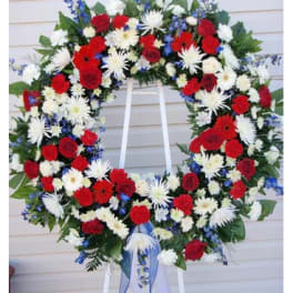 Large red, white, and blue floral wreath on a stand with ribbon