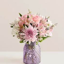 Pink and white mixed bouquet in a purple glass vase