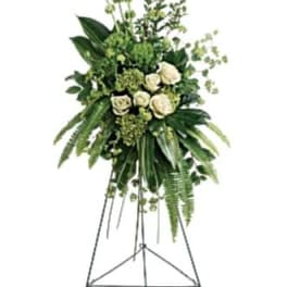 Tall white rose funeral spray on a metal easel