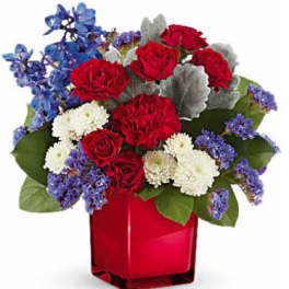 Red roses, white carnations, and blue flowers in a red vase