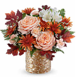 Peach roses and orange flowers in a woven basket