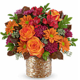 Orange and red mixed bouquet in a woven basket vase