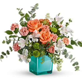 Peach roses and pink carnations in a turquoise glass vase