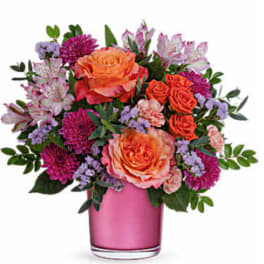 Pink and orange mixed flower arrangement in a pink vase