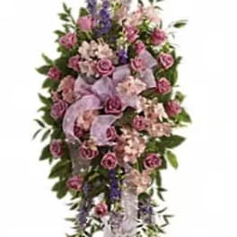Tall standing floral spray with pink roses and purple flowers on a white ribbon stand