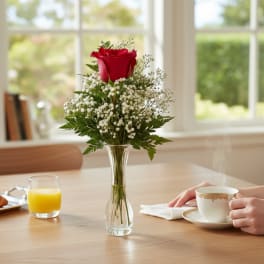 Red rose arrangement in a clear glass vase on a table