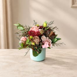Pink and red floral arrangement in a light blue vase