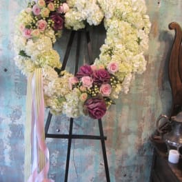 Heart-shaped floral wreath on an easel with pink and white flowers