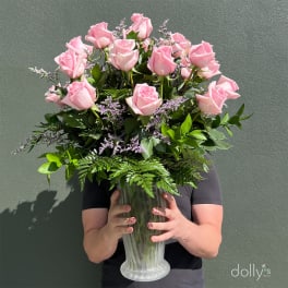 Pink roses in a clear glass vase with purple filler flowers
