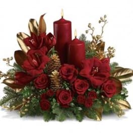 Red roses with candles and gold accents in a holiday centerpiece