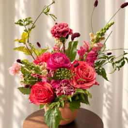 Pink and coral floral arrangement in a peach vase