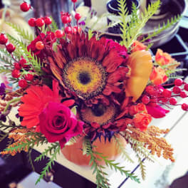 Bright mixed bouquet with sunflowers, roses, and orange blooms in a vase