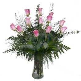 Pink roses arranged in a clear glass vase with greenery
