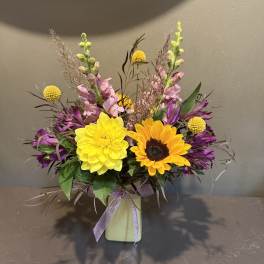 Colorful bouquet with yellow and orange blooms in a pale vase