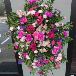 Large pink and purple funeral spray on a stand