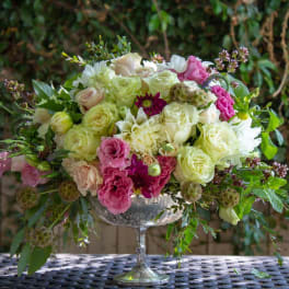 Mixed pink and white floral arrangement in a silver pedestal vase
