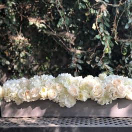Low floral arrangement of white and blush roses in a rectangular container