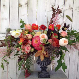 Mixed bouquet in a dark urn vase with pink, red, white, and peach blooms